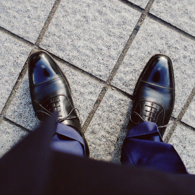 Image looking down at a pair of dress shoes on a gentleman